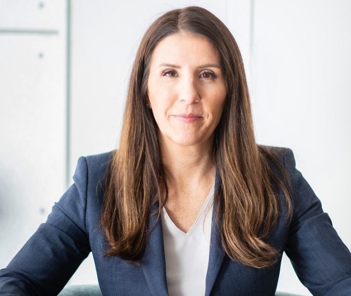 Cara Tangaro in a blue business suit sitting in a business chair