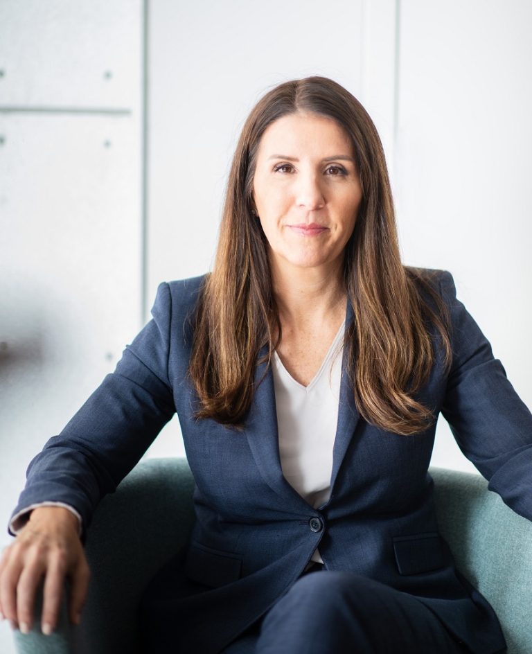 Cara Tangaro in a blue business suit sitting in a business chair