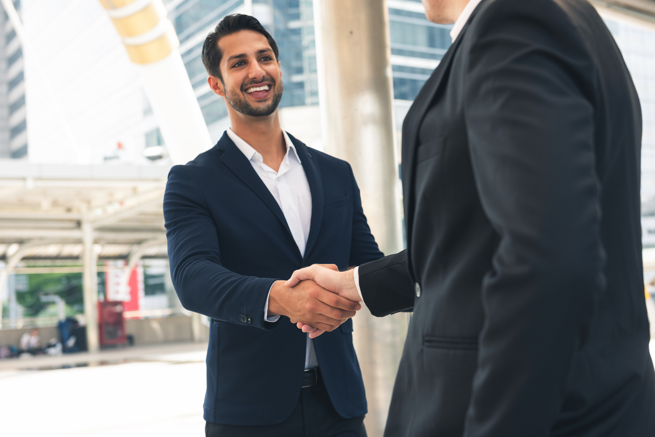 Handshake of 2 businessman in a black suit at outdoor, office located the business center city. Mergers and acquisitions for start greeting with good etiquette negotiation the success of both