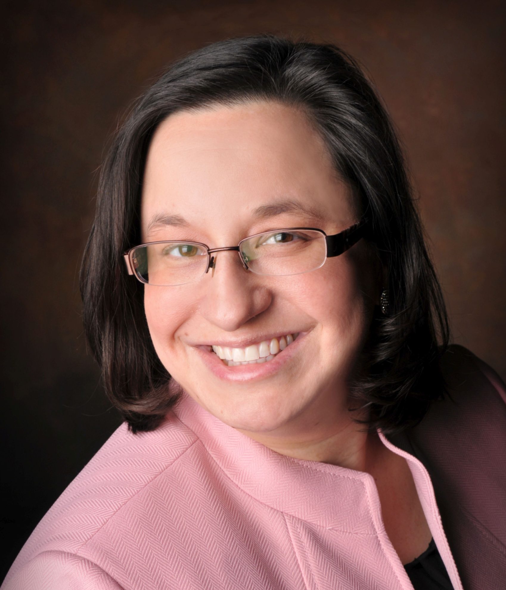 Headshot photo of Director of Professional Education at the Utah State Bar Michelle Oldroyd, who is wearing a pink jacket and black undershirt.