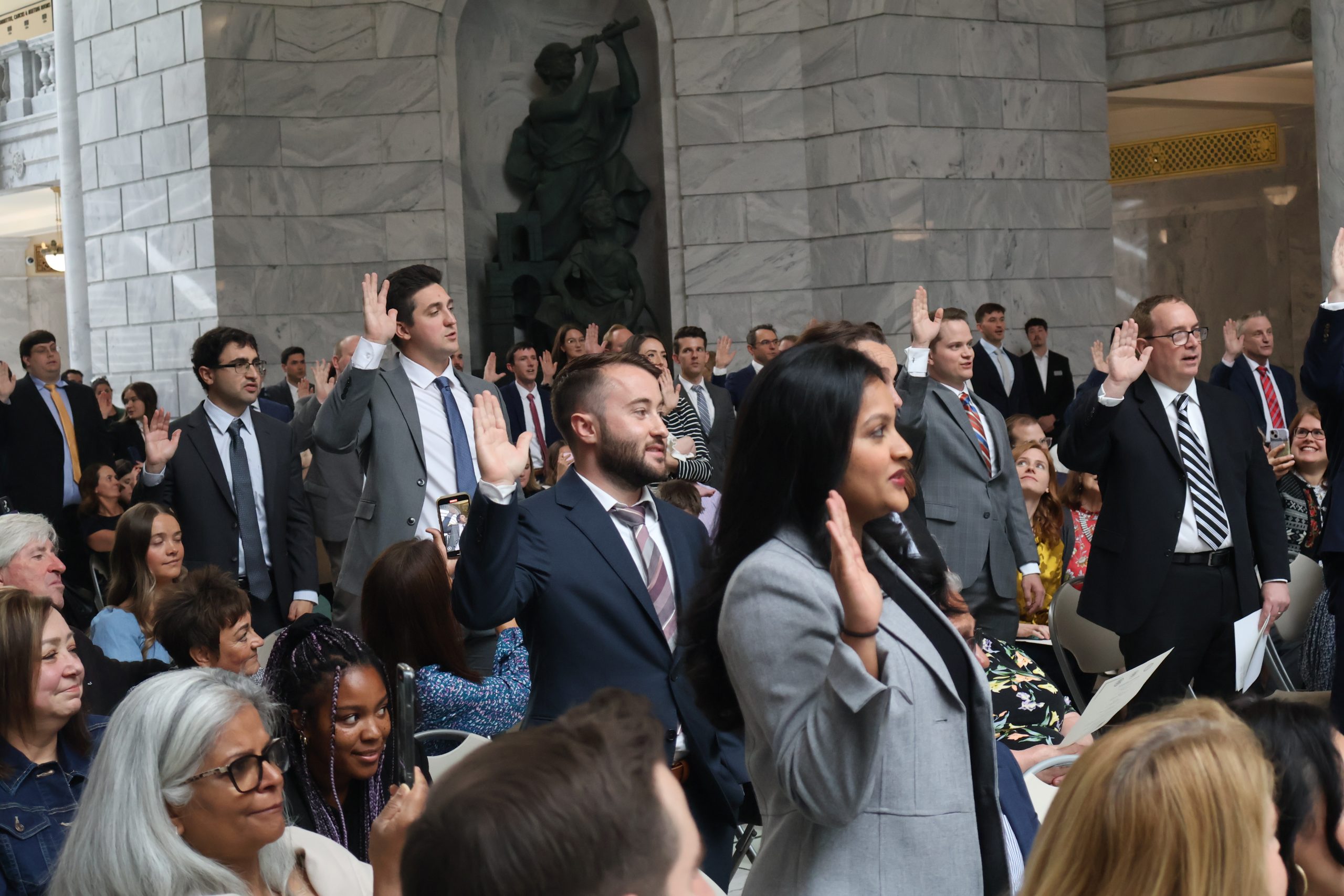 New lawyers taking the attorney oath with their right hands raised at the Admissions Ceremony in the Utah State Capitol, May 20, 2025