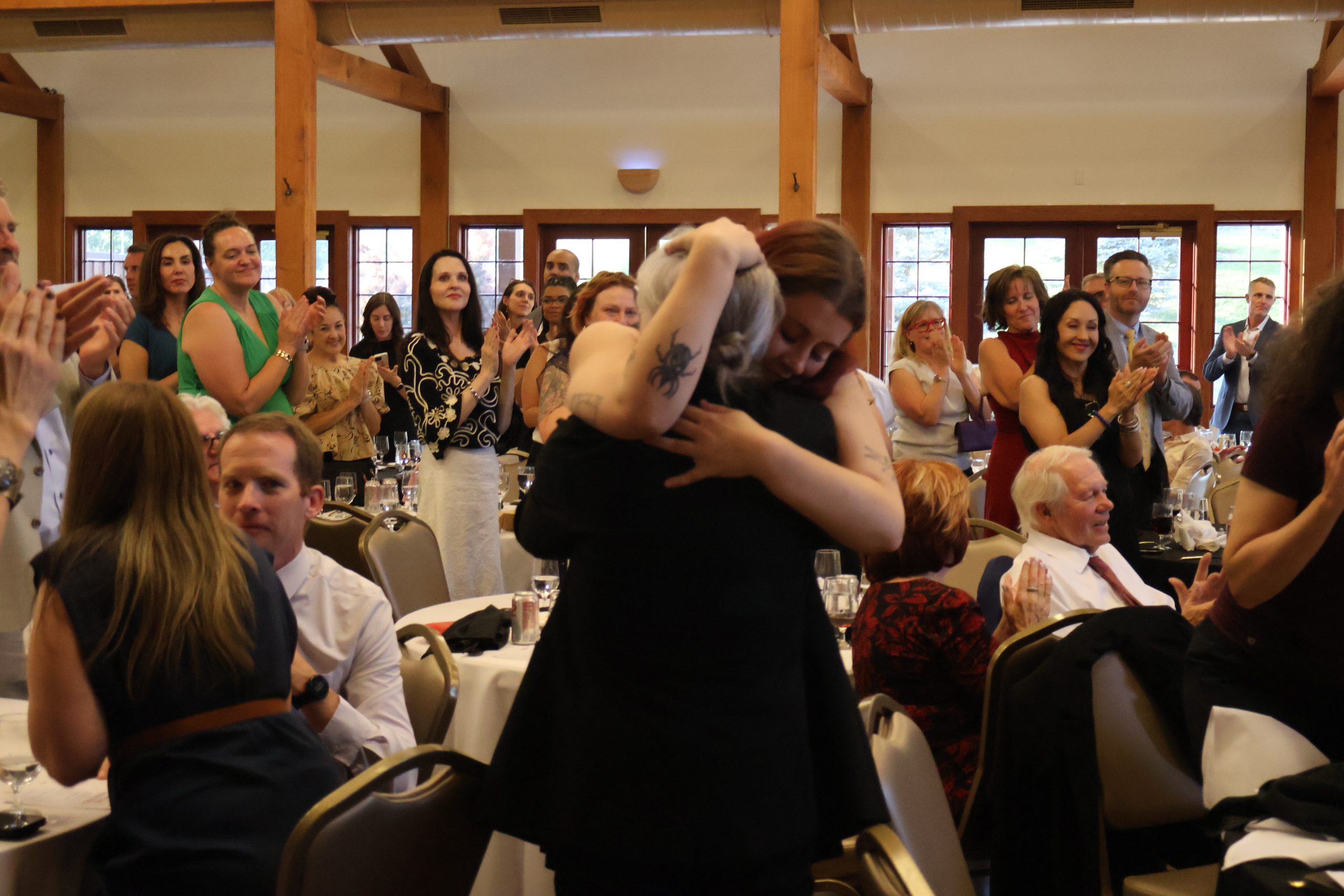 Prof. Jensie Anderson is welcomed with a hug by her daughter at the 2025 Annual Meeting, June 26, 2025.