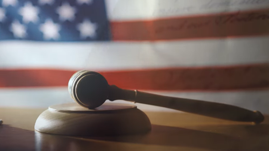 PHOTO - Gavel lying on a sound block on a table with the American flag in the background